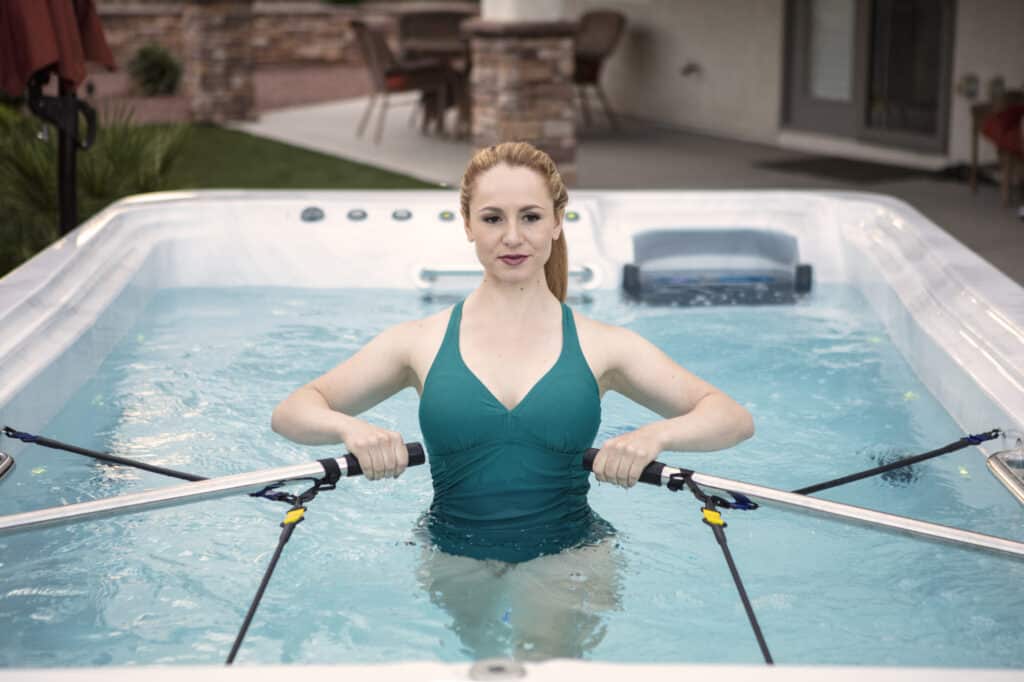 woman doing swim spa training with rowing bars and warm water