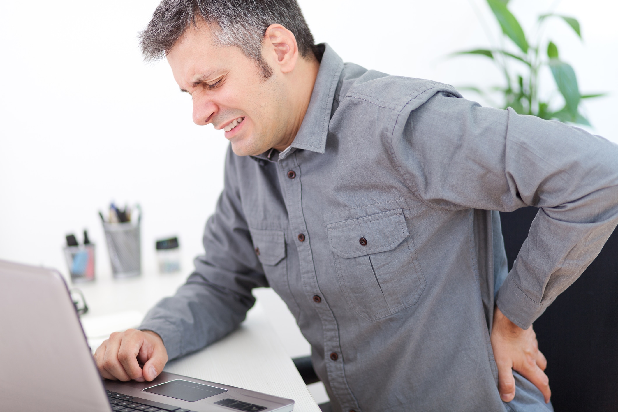 man experiencing back pain from sitting at a desk for too long