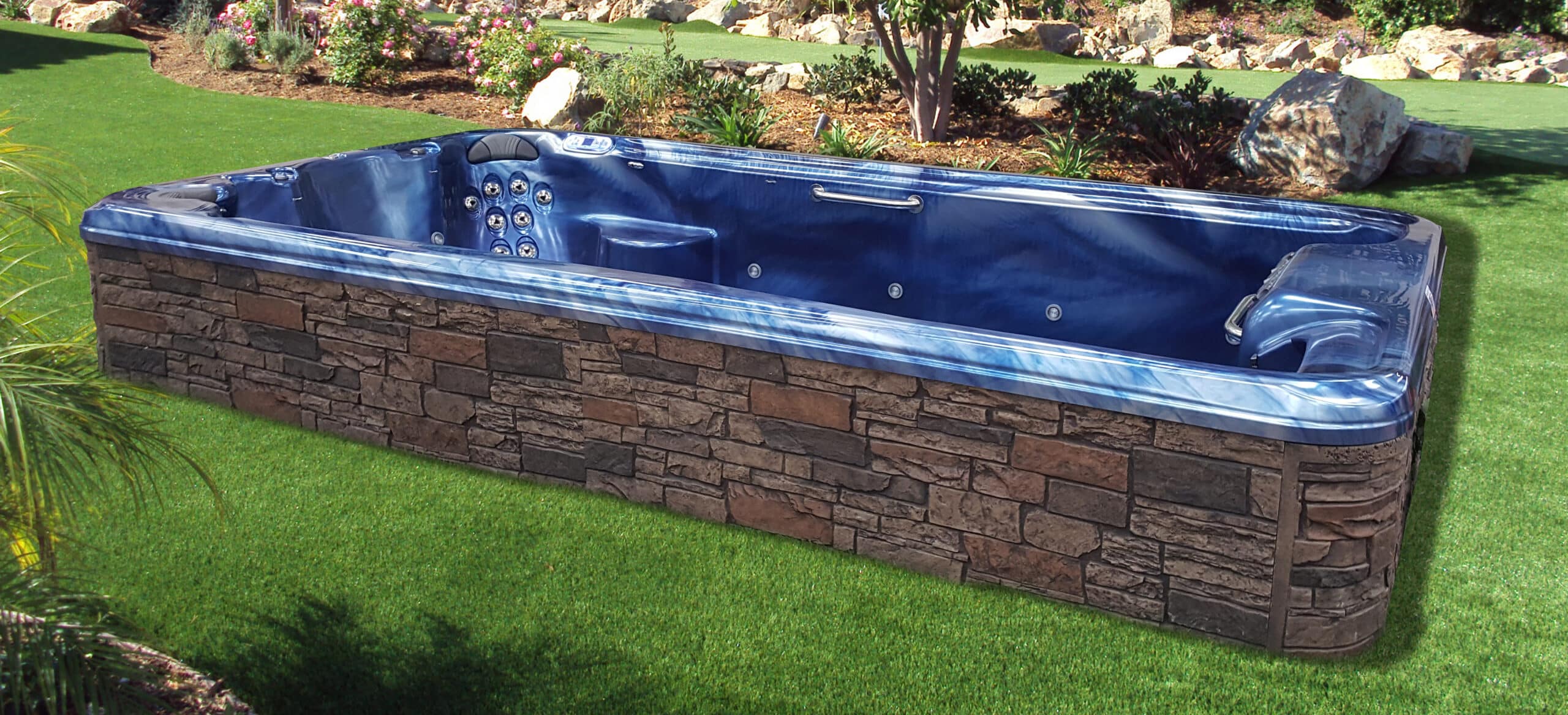 a blue swim spa in a green backyard with landscaping